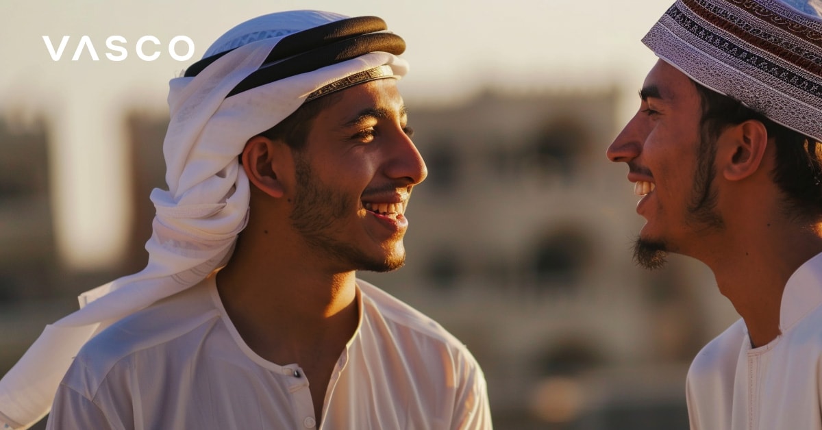 Twee mannen in traditionele Arabische kleding lachen naar elkaar en demonstreren hoe je hallo zegt in het Arabisch.