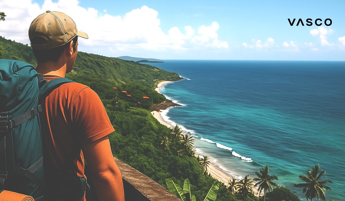 Een jonge jongen staat op een heuvel op een boomstam en kijkt uit over de oceaan.