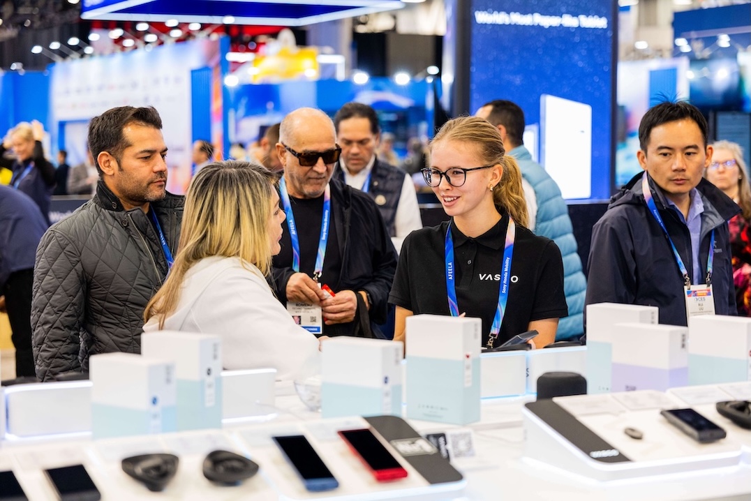 Een groep mensen staat glimlachend te praten bij de stand van Vasco Electronics op CES 2026.