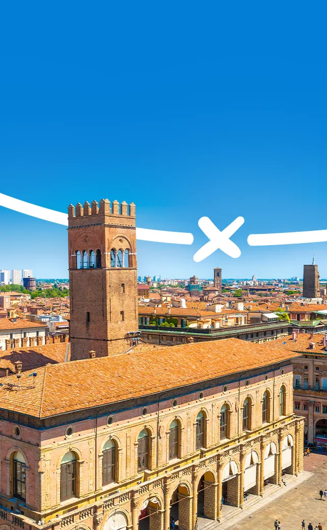 Een luchtfoto van het historische stadsbeeld van Bologna, Italië, met zijn rode bakstenen, onder een helderblauwe hemel.