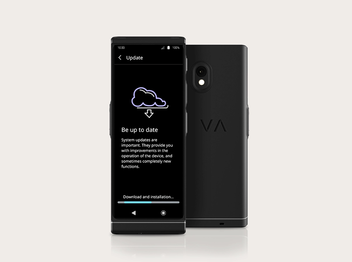Een studiofoto van de Vasco Translator V4 waarop de interface voor systeemupdates te zien is. Twee zwarte apparaten staan naast elkaar: één met de voorkant naar voren en één met de achterkant naar voren. Op het scherm is een wolkpictogram met een downloadpijl te zien, de kop „Blijf up-to-date“ en onderaan een voortgangsbalk met het opschrift „Downloaden en installeren...“. Op de achterkant zijn de camera met dubbele lens en het „VA“-logo in reliëf te zien.