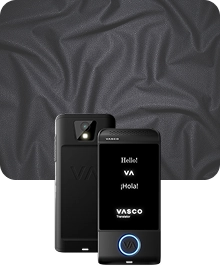 Een productfoto waarop een zwart Vasco Translator-apparaat vanuit twee hoeken te zien is tegen een donkere achtergrond van gestructureerde stof. Het apparaat aan de linkerkant toont de achterkant, met de nadruk op een cameralens met flitser en een 